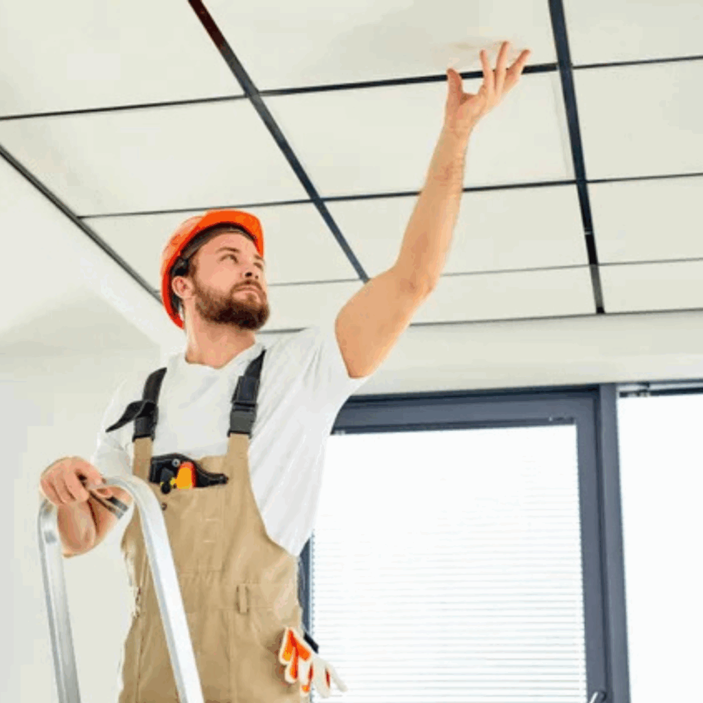 Worker installing washable ceiling tiles for commercial kitchens