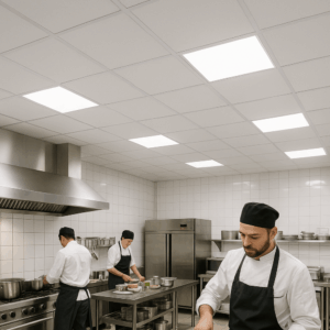 Chefs working in a commercial kitchen with white ceiling tiles and bright built-in lighting.